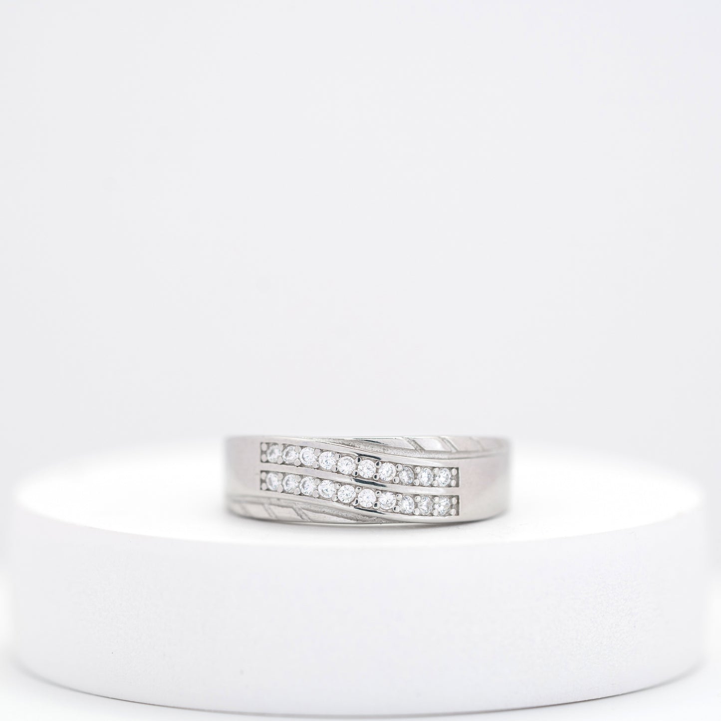 Silver ring with embedded diamonds on a white stand