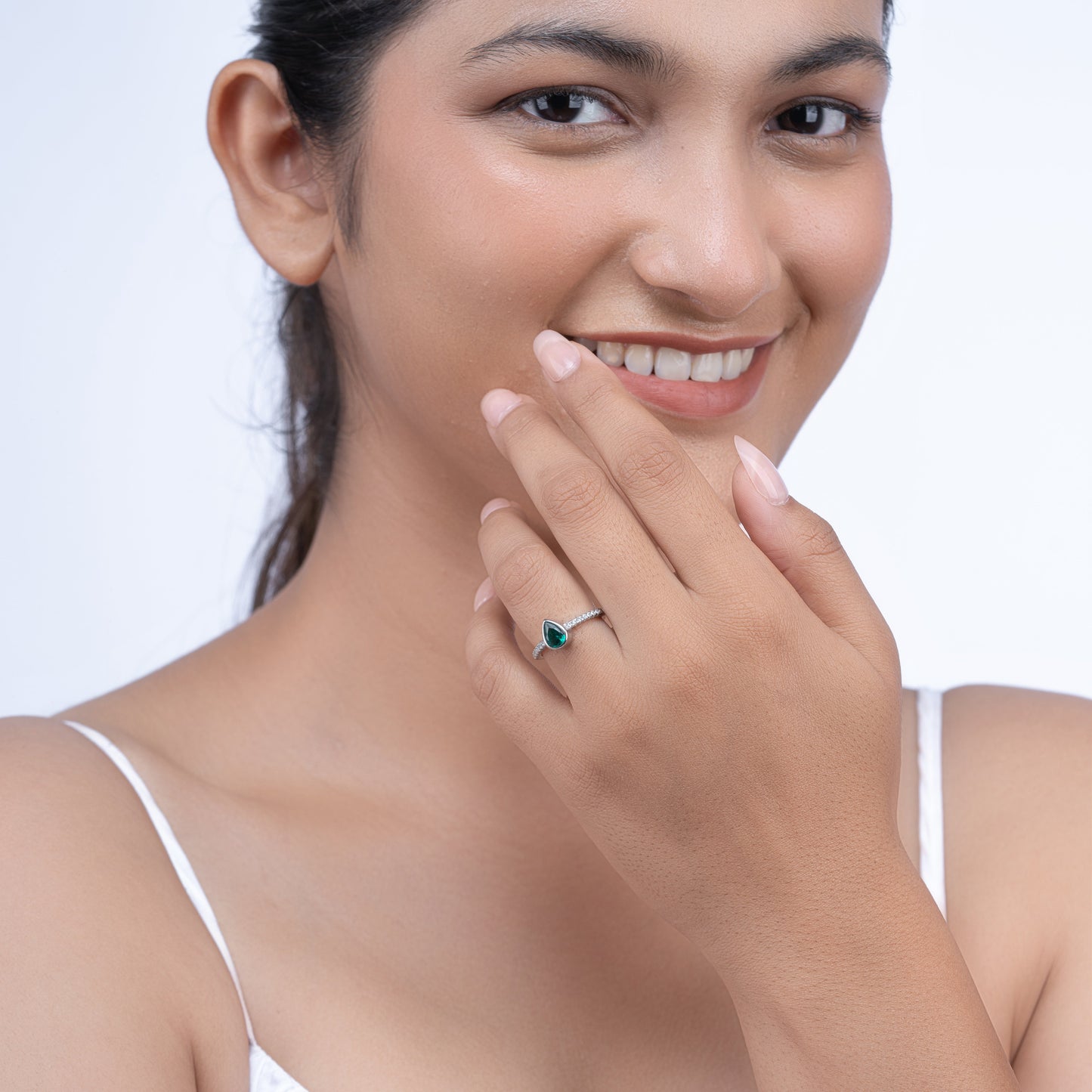 Elegant silver teardrop emerald center ring and side diamonds on a model's hand