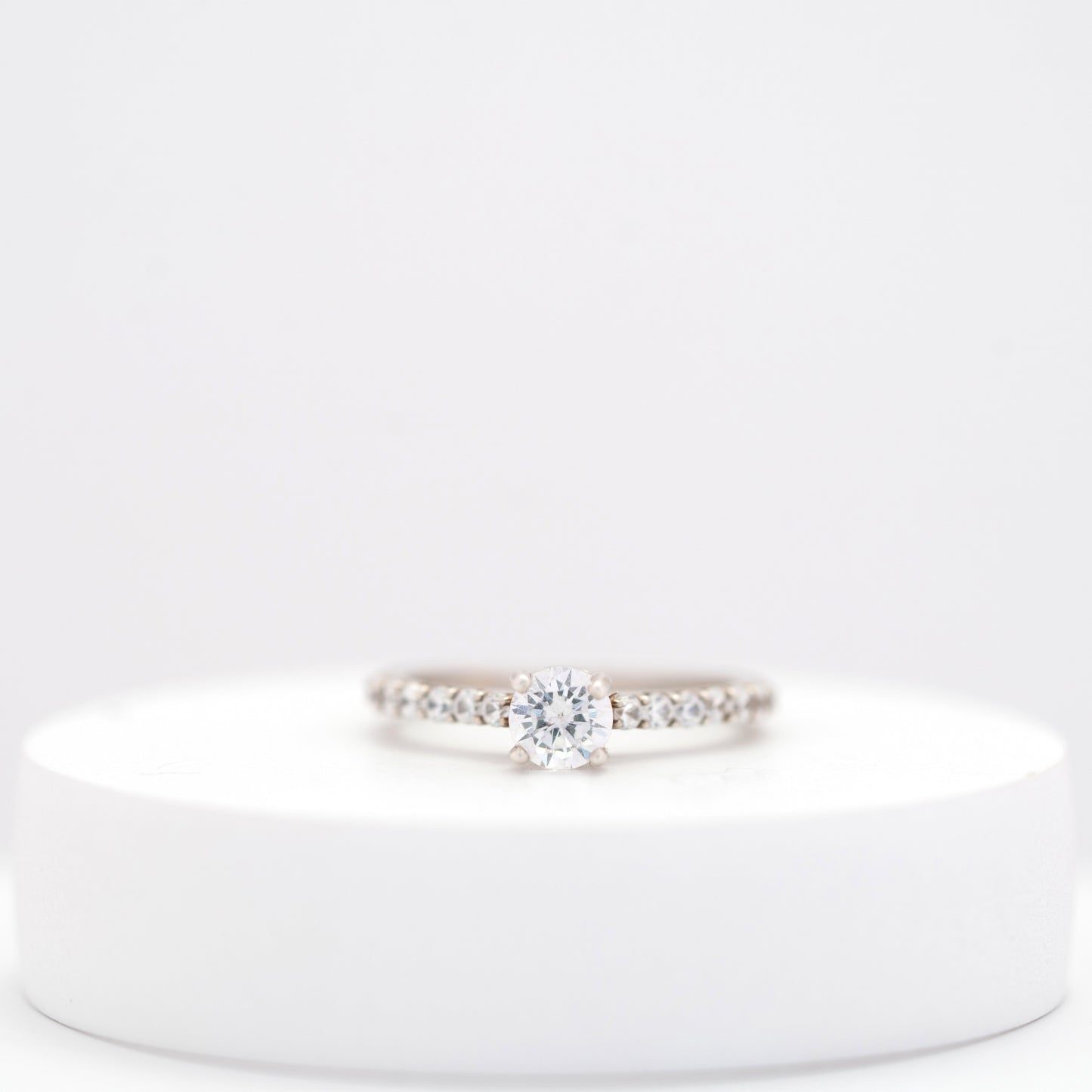 Elegant silver ring for women with a sleek, minimalist design displayed on a white stand