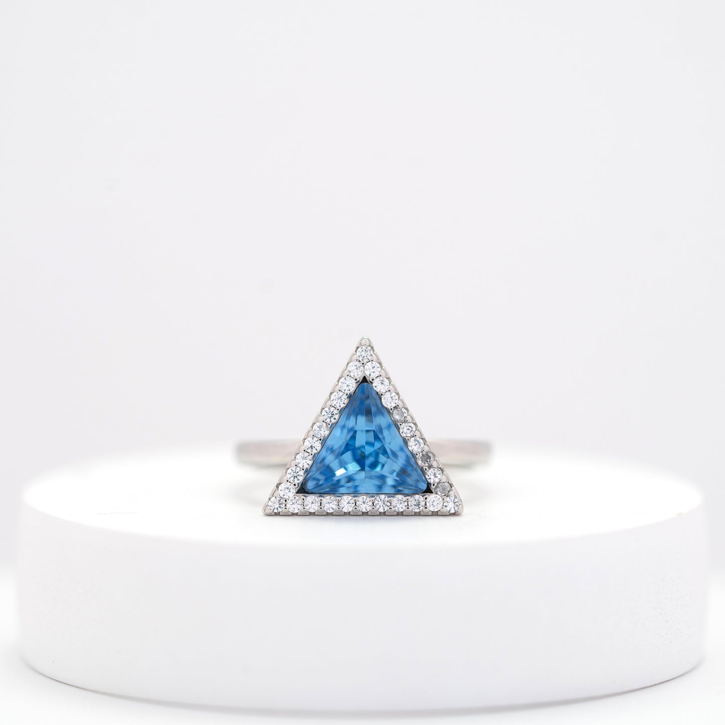 front view of sterling silver ring for woman with a blue stone on a white stand