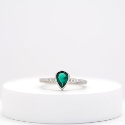 front view of elegant silver ring with teardrop emerald center stone and side diamonds