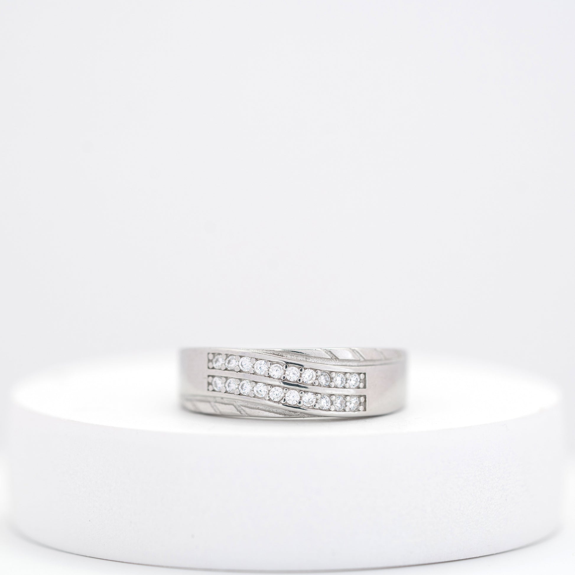 Silver ring with embedded diamonds on a white stand