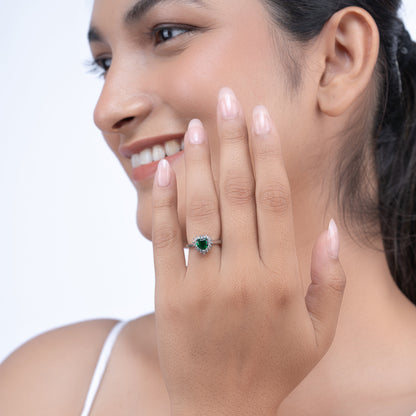 Elegant emerald heart diamond cluster ring on a model's hand 
