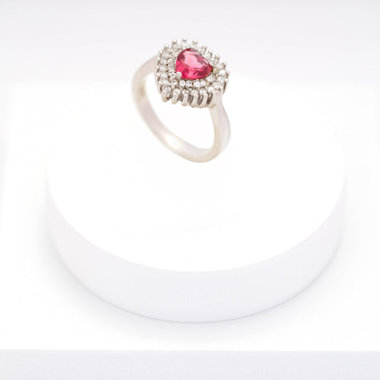 Silver ring with heart-shaped pink sapphire and diamond halo on a white stand