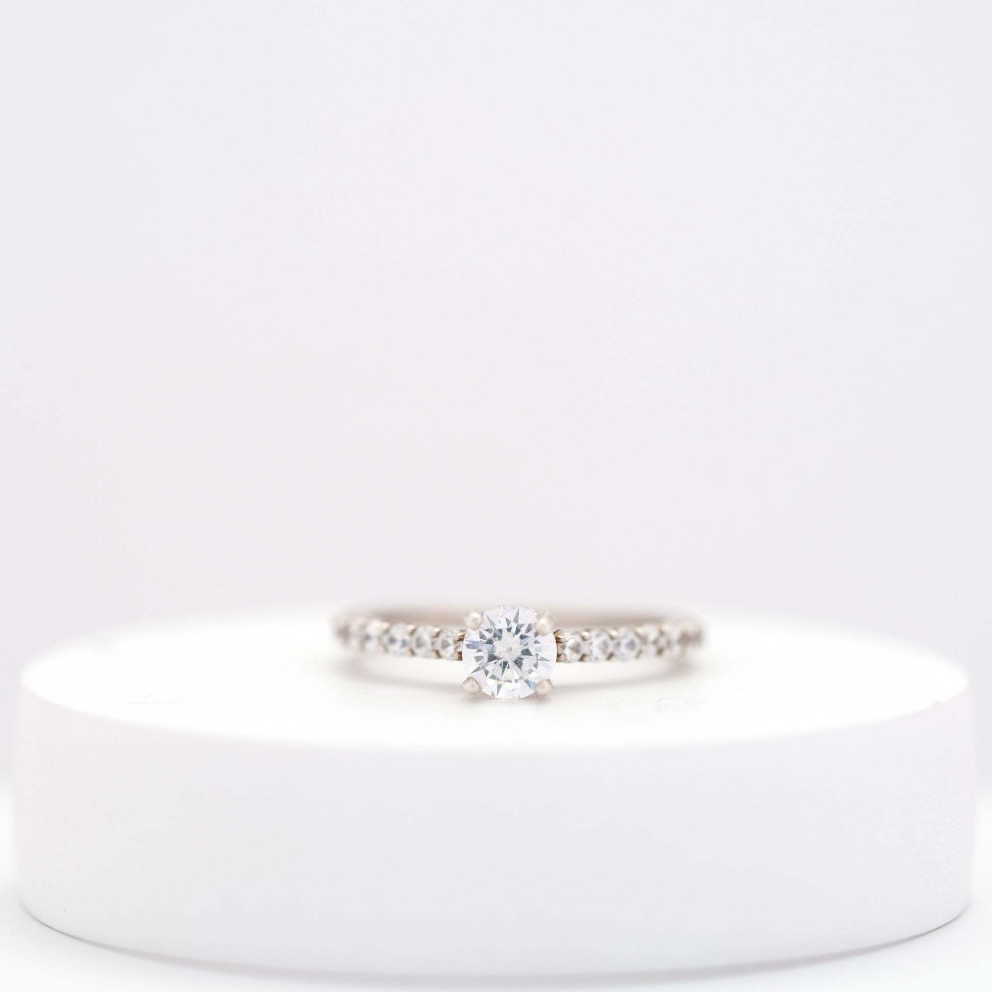 Elegant silver ring for women with a sleek, minimalist design displayed on a white stand