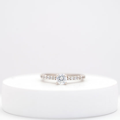 Elegant silver ring for women with a sleek, minimalist design displayed on a white stand