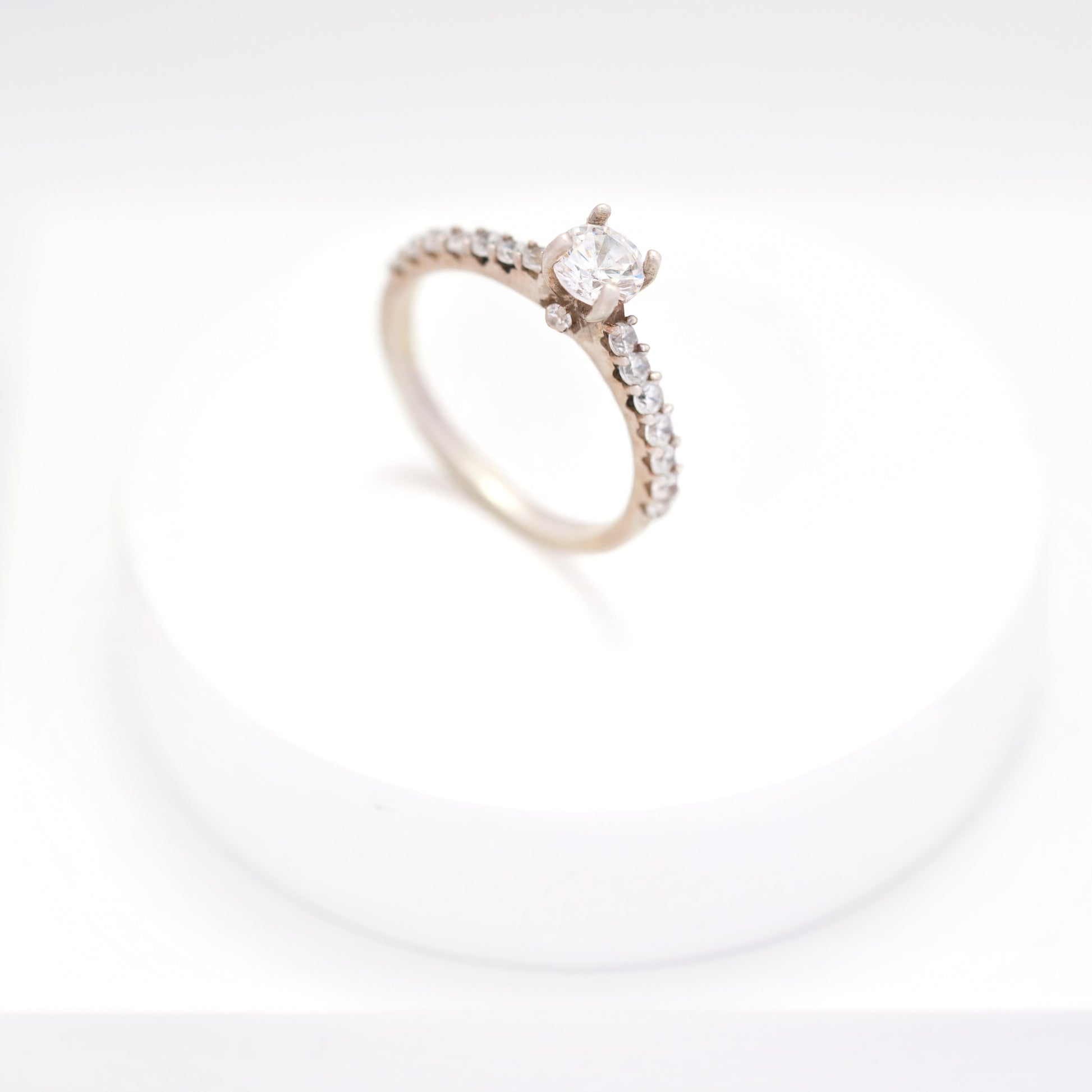 Elegant silver ring for women with a sleek, minimalist design, displayed on a white pedestal