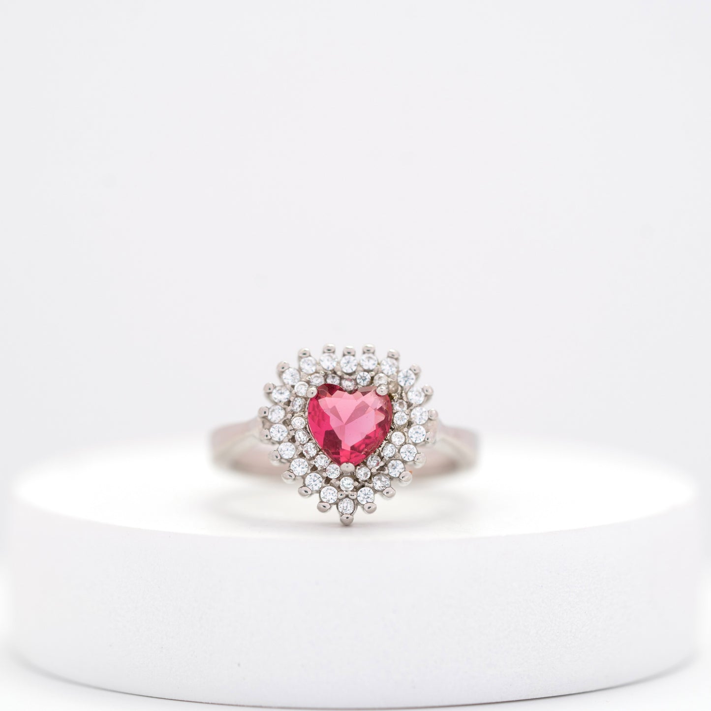 front view of dainty silver ring featuring a pink heart gem and brilliant diamond halo. 