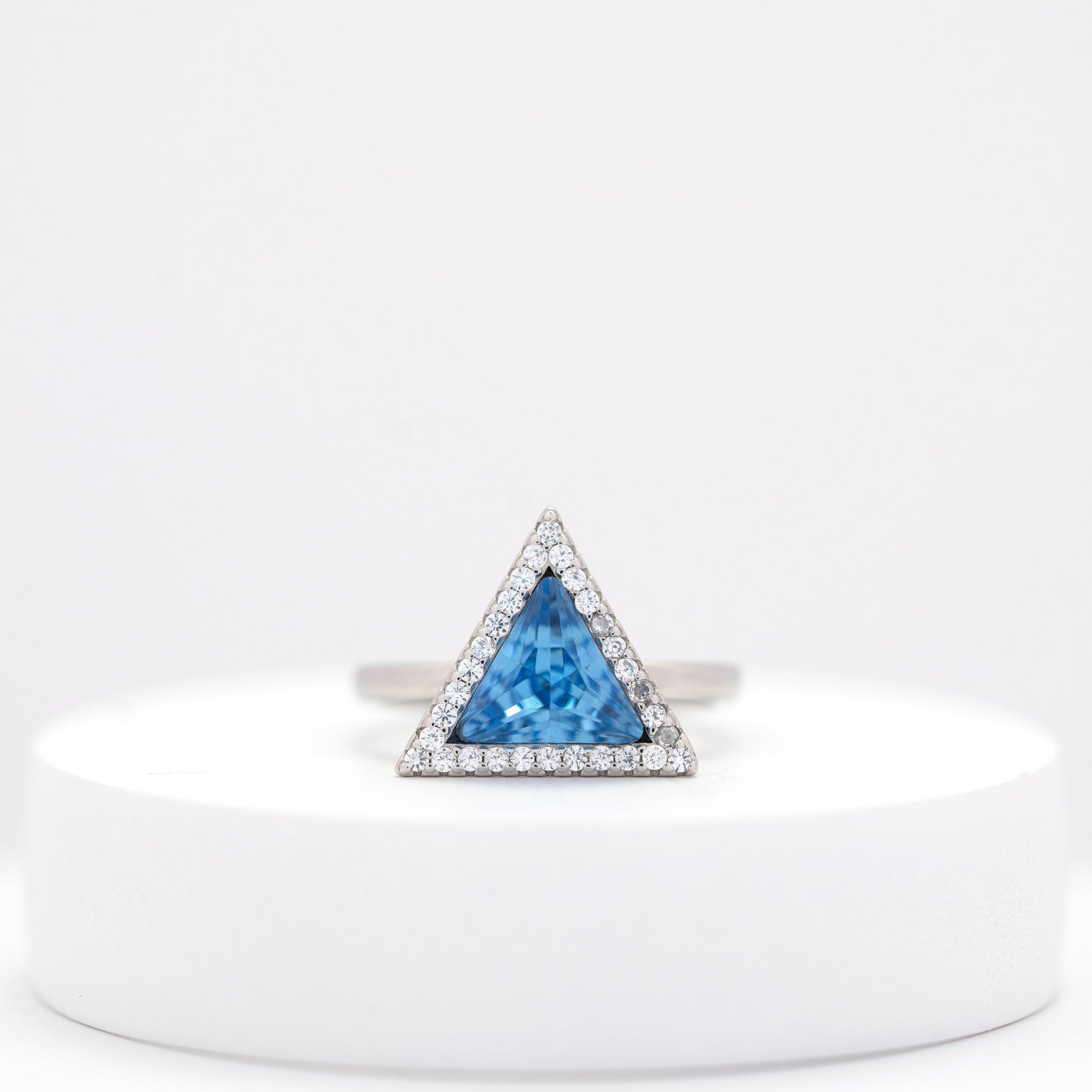 front view of sterling silver ring for woman with a blue stone on a white stand 