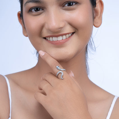 Woman wearing a silver snake-shaped ring with embedded stones, smiling and touching her face